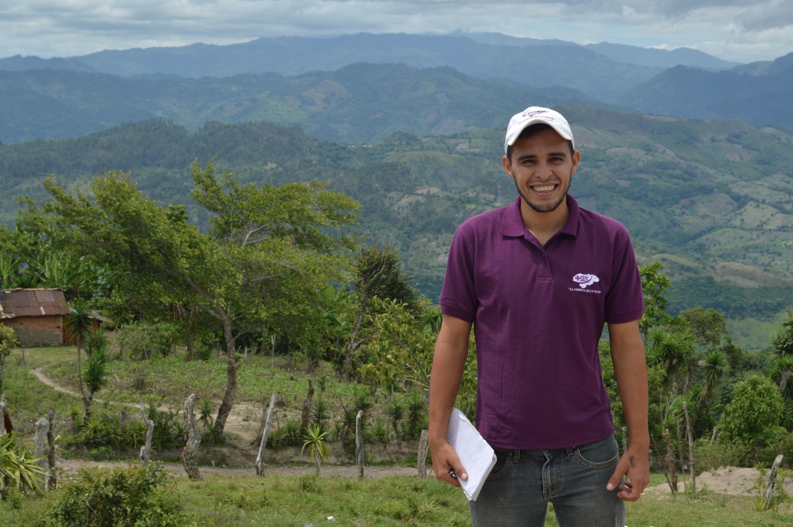 A member of the Human Nature Lab research team poses in front of a green field in Honduras.