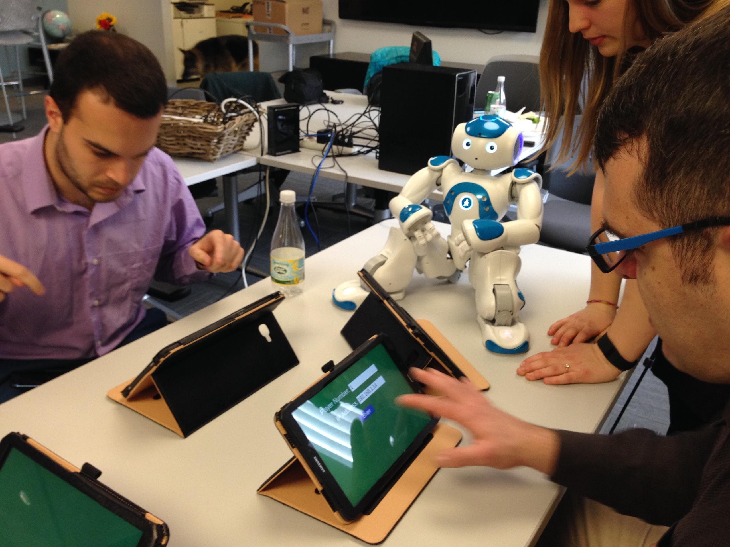 A group of participants play a tablet based game with a physical robot.